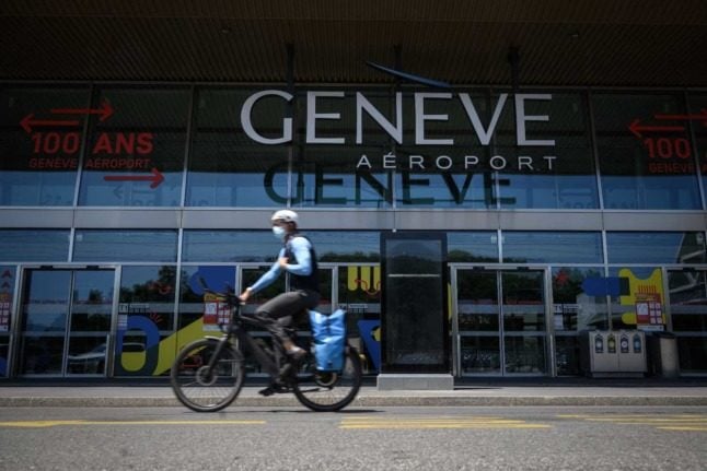 A person in a mask rides their bike past Geneva Airport