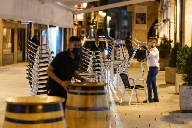 Bar staff clear up chairs and tables at a bar terrace in downtown Burgos, in Castilla and Leon region. 