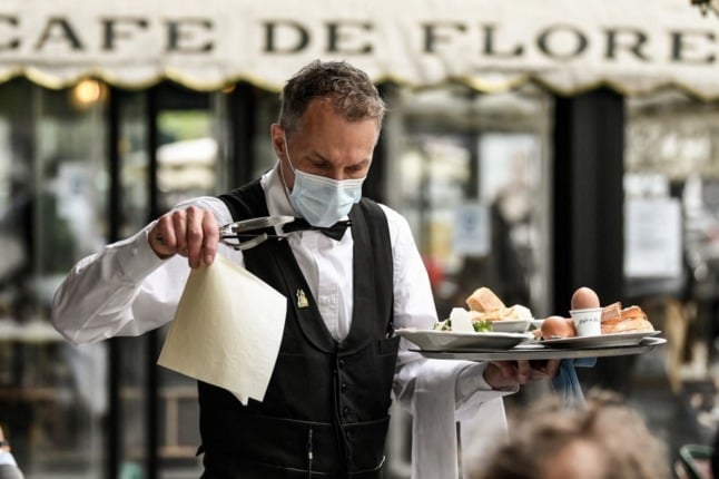 A waiter in Paris carries food to the table. Many voilà's are likely to be exchanged.