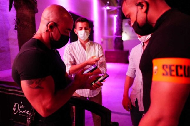 Security guards check a person's Covid certificate at the door to a club