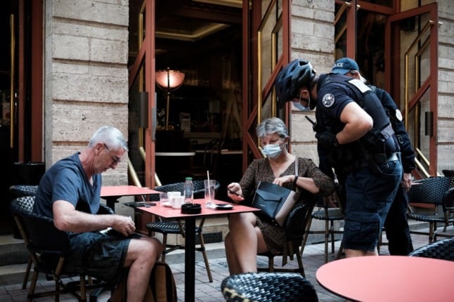 Police check health passes at a café in France. 