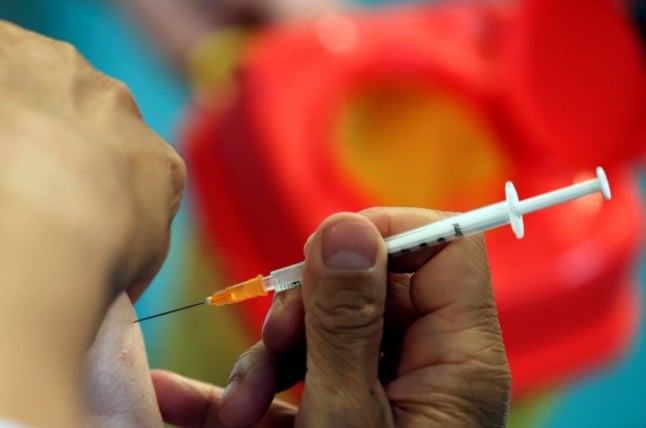 Close-up image of a syringe filled with Covid-19 vaccine going into an older person's arm