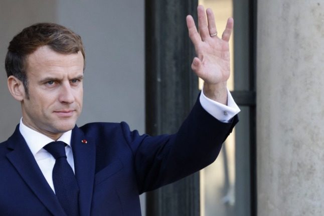 French President Emmanuel Macron waves from the stairs of the Elysee Palace.