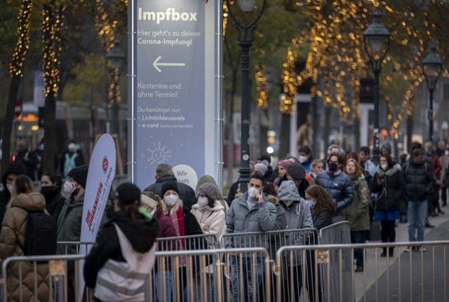People queue for Covid-19 vaccines outside a Vienna Christmas market. 