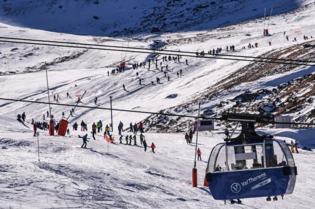 People ski down a slope near a cable car at Val Thorens ski resort, in the French Alps