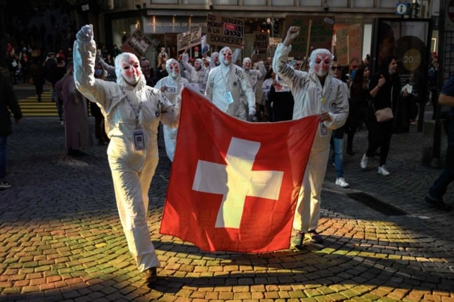 Anti-Covid protesters carry a Swiss flag in Lausanne