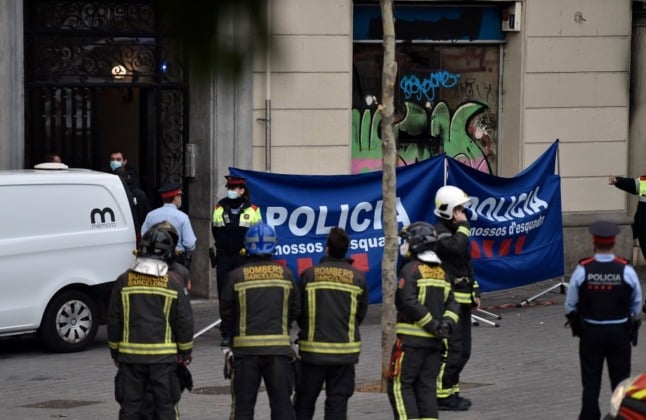 Police and firefighters gather outside an abandoned building where a blaze broke out early on November 30, 2021 in Barcelona, killing four people. 