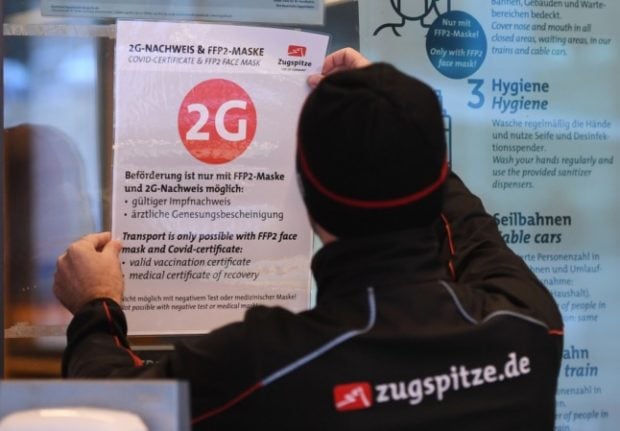 A Zugspitzbahn employee sticks a 2G notice up at the entrance to a cable car lift.