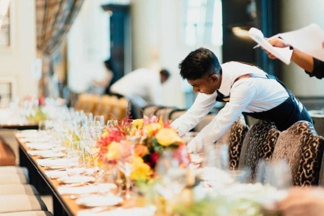 A waiter fixes a table arrangement