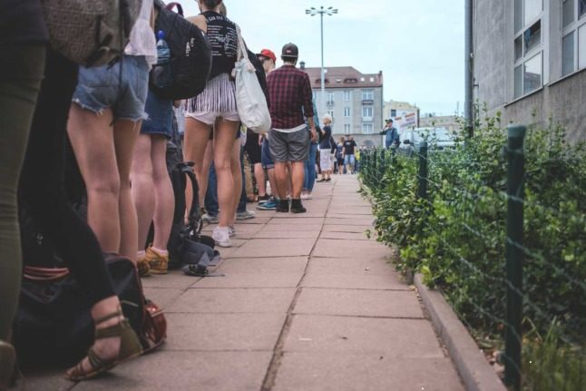 People lined up in a queue along a pavement path