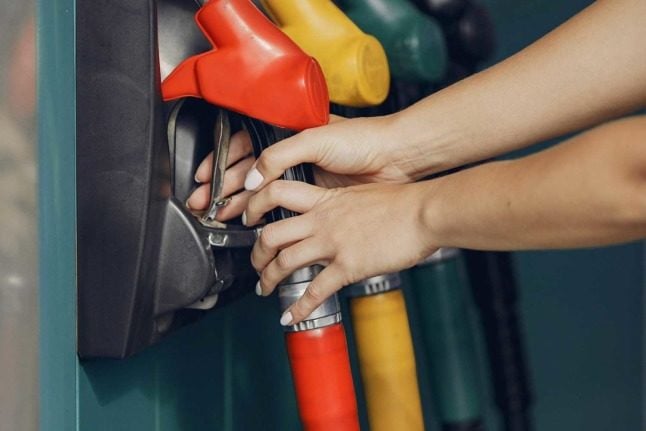 A person reaches for a petrol pump from a colourful selection