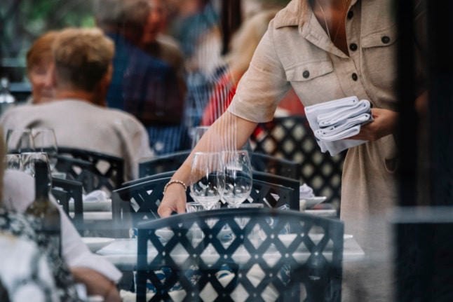 a woman setting a table at an outdoor restaurant serving area in stockholm