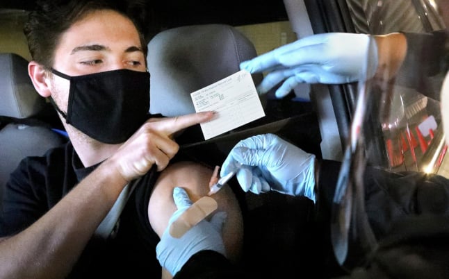 a man getting vaccinated while holding his CDC card