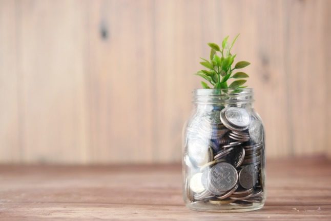 Here's how you can claim your Norwegian pension from another country. Pictured is a plant growing out of a money jar to signal investments growing. 