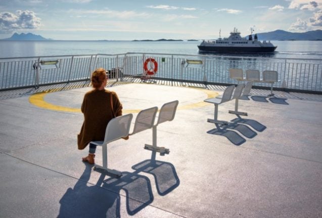 Pictured is a woman sat on a ferry in Norway, watching another ferry sail by. 