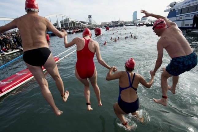 Participants jumps into the water during the 109th edition of the 'Copa Nadal' (Christmas Cup) swimming competition in Barcelona's Port Vell on December 25, 2018. - The traditional 200-meter Christmas swimming race gathered more than 300 participants on Barcelona's old harbour. (Photo by Josep LAGO / AFP)