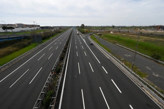 A general view taken from a bridge shows a few cars driving through a deserted highway leading to Rome's Fiumicino international airport 