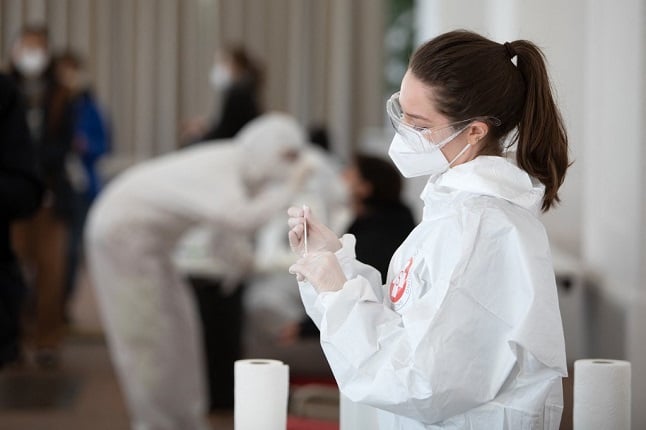 A health worker prepares a coronavirus antigen rapid test at the new coronavirus test center in the Orangery of the Schoenbrunn Palace. (Photo by ALEX HALADA / AFP)