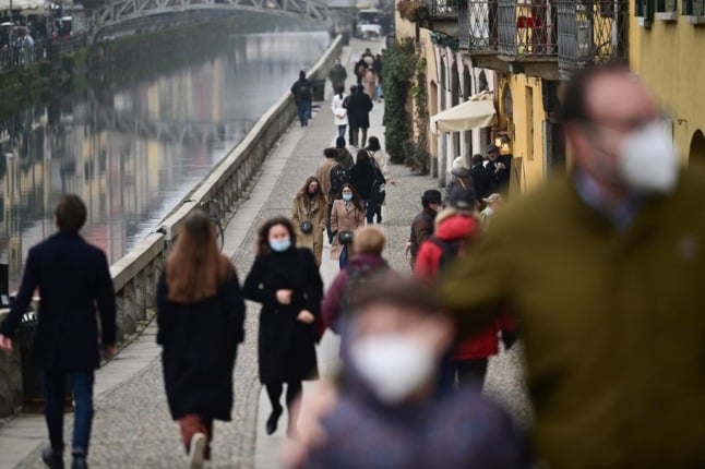 People wear face masks as they walk in Milan.