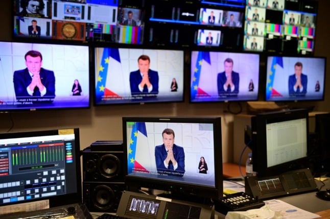 French President Emmanuel Macron appears on several TV screens in a broadcaster's control room