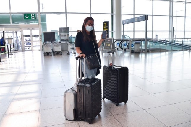 A lady waits with her bags at an airport. 