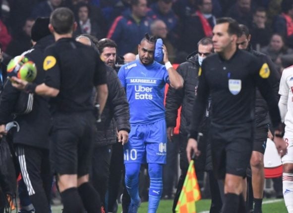 Marseille's French midfielder Dimitri Payet, surrounded by officials, leaves the field holding an ice pack to his head