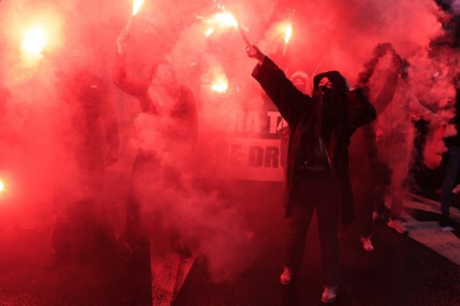 Demonstrators hold flares during a rally to protest against French far-right 2022 presidential candidate Eric Zemmour in Paris