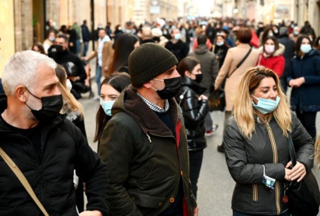 People wear face masks as they walk in central Rome. 