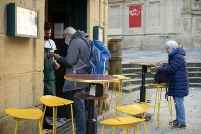 A waiter checks a customer's Covid-19 health pass in front of a bar of the Spanish Basque city of San Sebastian on December 15, 2021, as it becomes mandatory in the Basque Country in restaurants, bars, sports centres, hospitals, gyms, nursing homes and at indoor cultural events. (Photo by ANDER GILLENEA / AFP)