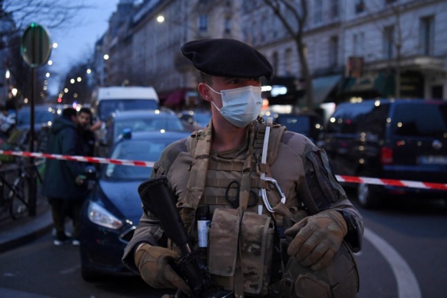 A French soldier stands on guard near a hardware store where two women were taken hostage on Monday