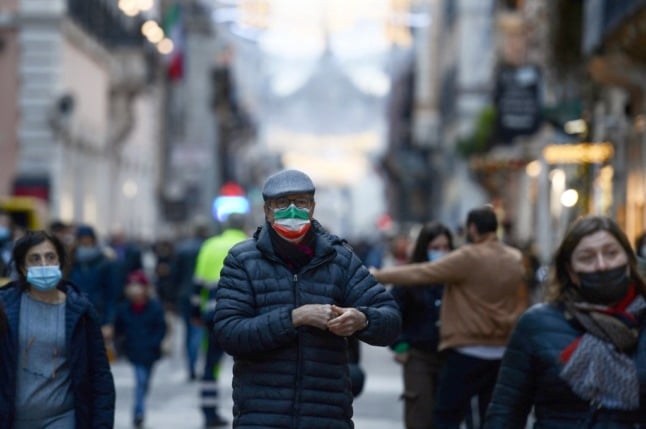 People wear face masks as they walk in central Rome.