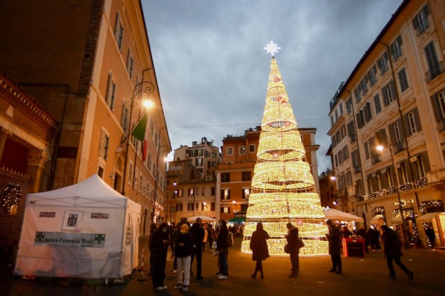 Bystanders wait outside a pharmacy to get tested for coronavirus (Covid-19) before Christmas, in Rome, on December 23, 2021.