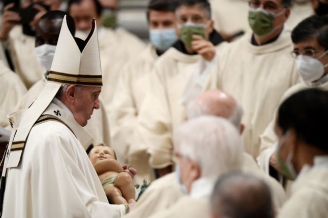 Pope Francis holds a figurine of baby Jesus during the Christmas Eve mass at St Peter's Basilica in the Vatican