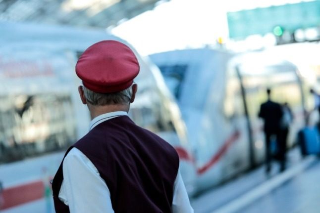 A conductor gives a departure signal for an ICE train on the platform at Berlin Central Station.