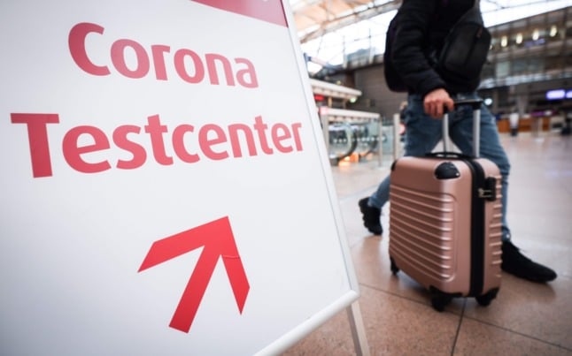 A passenger walks next to a Covid test centre sign in Hamburg airport