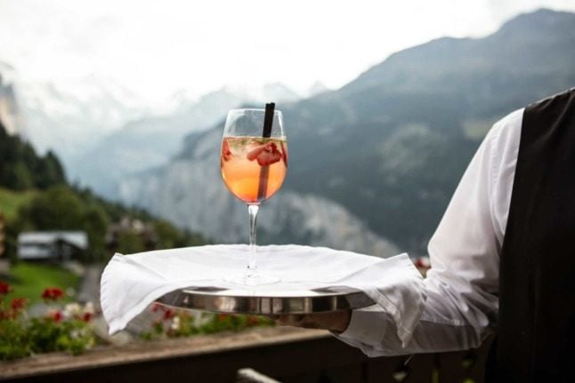 A waiter holds a drink in the Swiss Alps