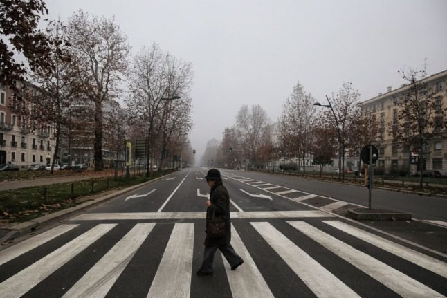 A pedestrian crosses Milan's empty Corso Sempione during a previous car ban.