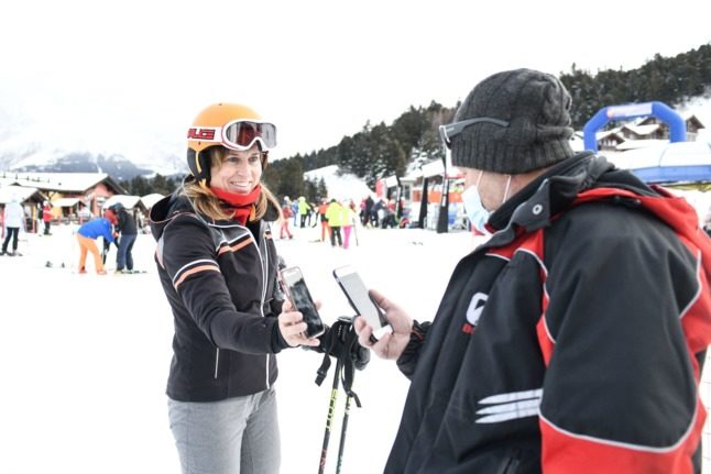 A woman shows her health pass on the ski slopes in Veneto, Italy.