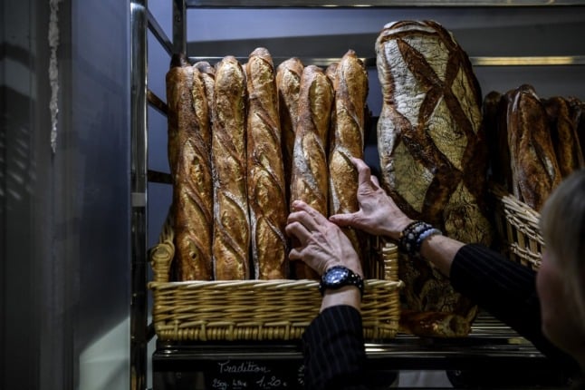 A baker reaches for baguettes in Paris. 
