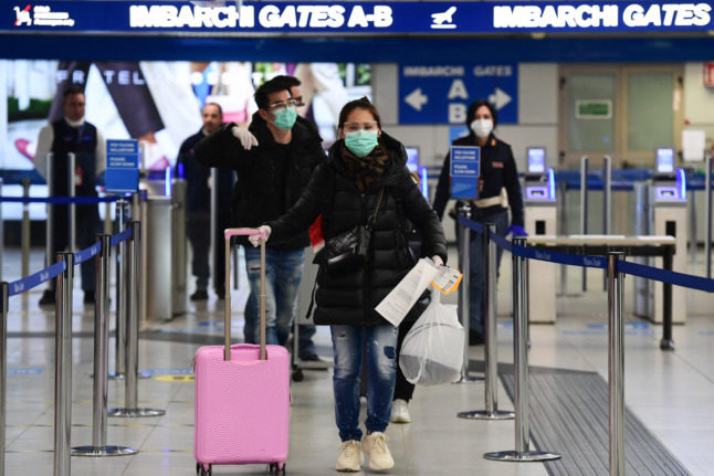 Passengers wearing protective masks walk across a terminal at Milan's Linate airport.