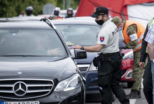 A Slovak police officer checks the papers of travelers crossing the Bratislava-Berg border crossing between Austria and Slovakia during the coronavirus COVID-19 pandemic on June 4, 2020.