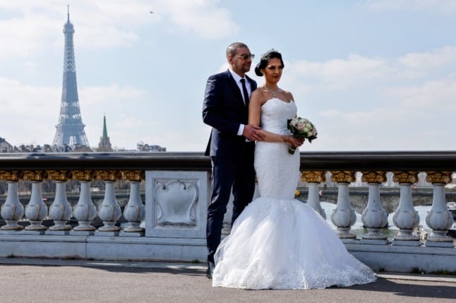 A newlywed couple pose on the Alexander III bridge in Paris.