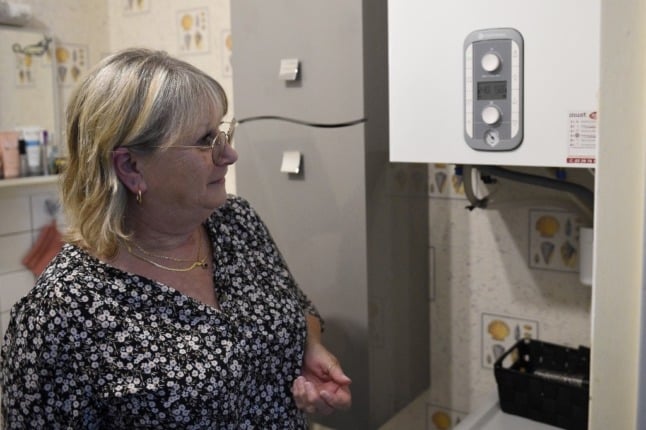 A lady pictured next to her gas boiler in France. 