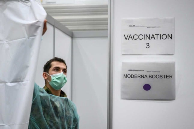 A member of the Swiss military pulls back the curtain at a vaccination site