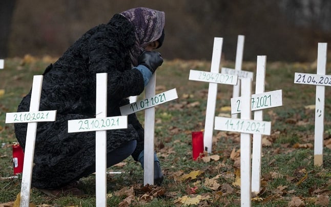 A woman places a symbolic cross in tribute to women killed in Austria in 2021, at Auer-Welschbach Park in Vienna, Austria on November 30, 2021. - Painted in blood red on an improvised memorial in Vienna, the number 31 is a stark reminder of a grim toll: the women killed by men in Austria last year. After several particularly horrific cases among the killings were widely reported in the media, the issue of femicide is now squarely under the spotlight. In a small, wealthy country where violent crime generally is rare, a public debate has begun, galvanising activists and forcing politicians to act. (Photo by ANDREA KLAMAR-HUTKOVA / AFP)