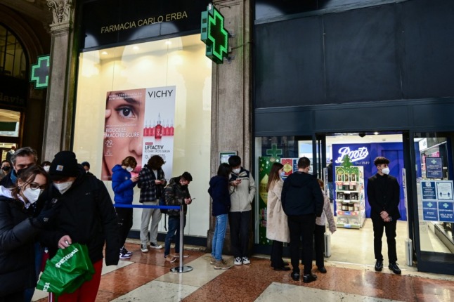 People wait outside a pharmacy for Covid testing in Milan.