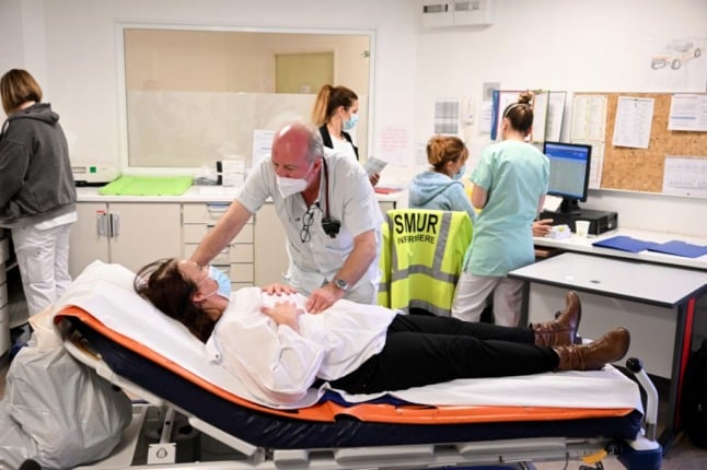 A doctor at a hospital talks to a patient who is lying on a bed at a hospital in southern France.