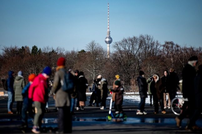 People walk in Berlin's Tempelhof airfield, with the TV tower in the background. 