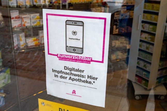 A sign in a pharmacy window advertises digital vaccine passes