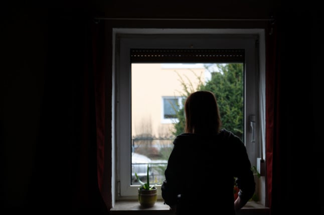 A woman looks out of the window while in quarantine